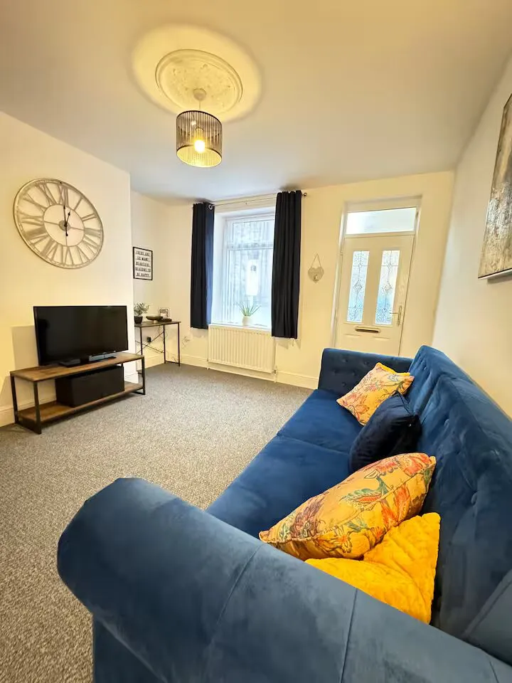 Living room with navy sofa and mustard cushions at the Flow Stays terraced house in central Barnsley