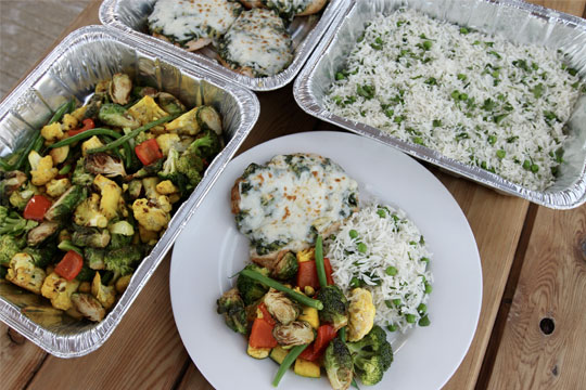 Hot buffet spread including chicken florentine, seasonal roasted vegetables, and rice pilaf prepared by Houston’s stress-free catering solution.