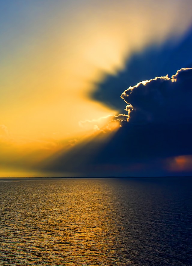 Bright yellow Sunrise over a lake with a dark cloud