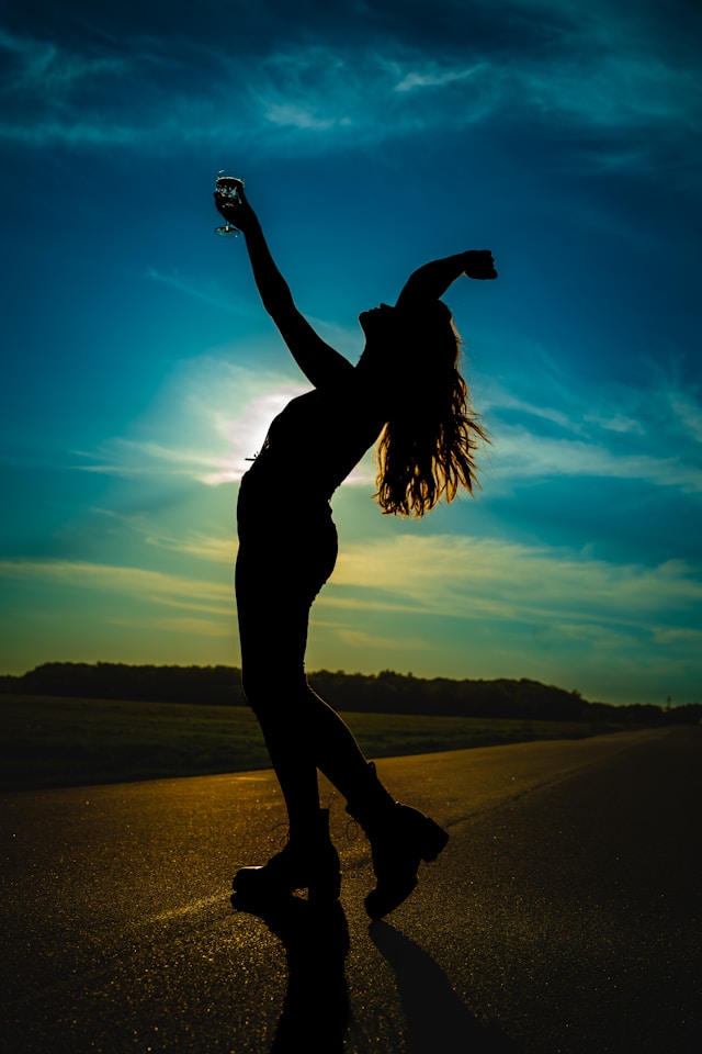 woman standing in the dusk arms stretched to the sky in celebration