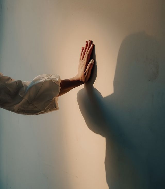 woman's hand touching her shadow o a wall