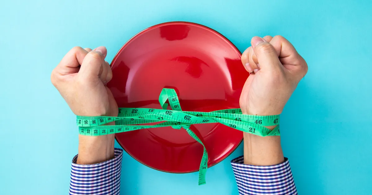 Woman's hands constrained by tape measure trying to use willpower for lasting health habits