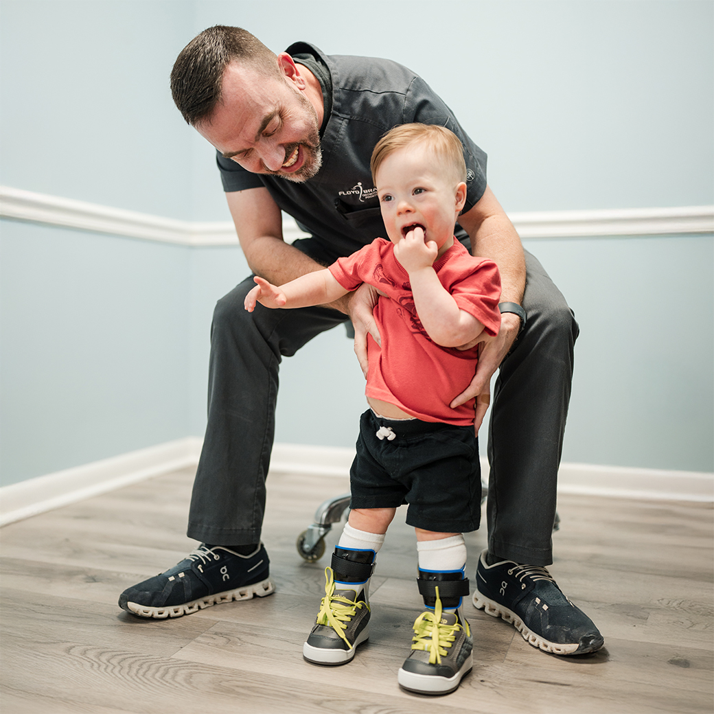 child with new AFOs practices standing with smiling floyd brace clinician