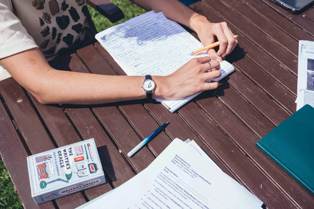 Close-up of  writer attending a KindWrite retreat writing in a notebook outside