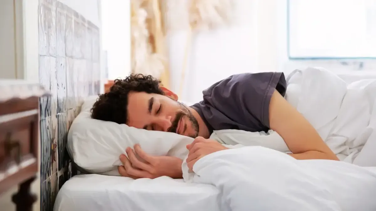 A man sleeping comfortably on his side with proper head and neck support from a pillow, demonstrating ergonomic sleep positions recommended by a Fort Mill chiropractor.