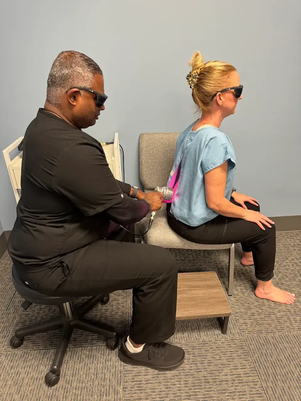 A clinician administering deep tissue laser therapy to a patient's lower back to reduce inflammation and accelerate pain relief in Fort Mill, SC.