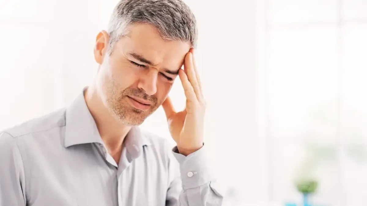 Middle-aged man holding his temple in severe pain from a migraine, seeking natural migraine relief in Fort Mill SC.