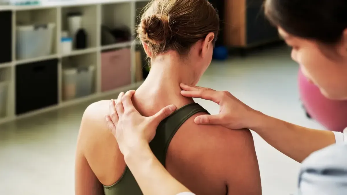 Chiropractor palpating a female patient's neck and cervical spine to locate nerve pressure causing migraines in Fort Mill SC.