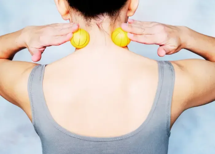 A woman performing self-myofascial release on neck trigger points using massage balls for natural myofascial pain relief in Fort Mill SC.