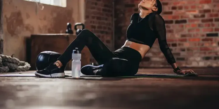 Woman taking a rest break during a gym workout to modify activity while recovering from foot pain with care from a plantar fasciitis chiropractor in Fort Mill, SC.