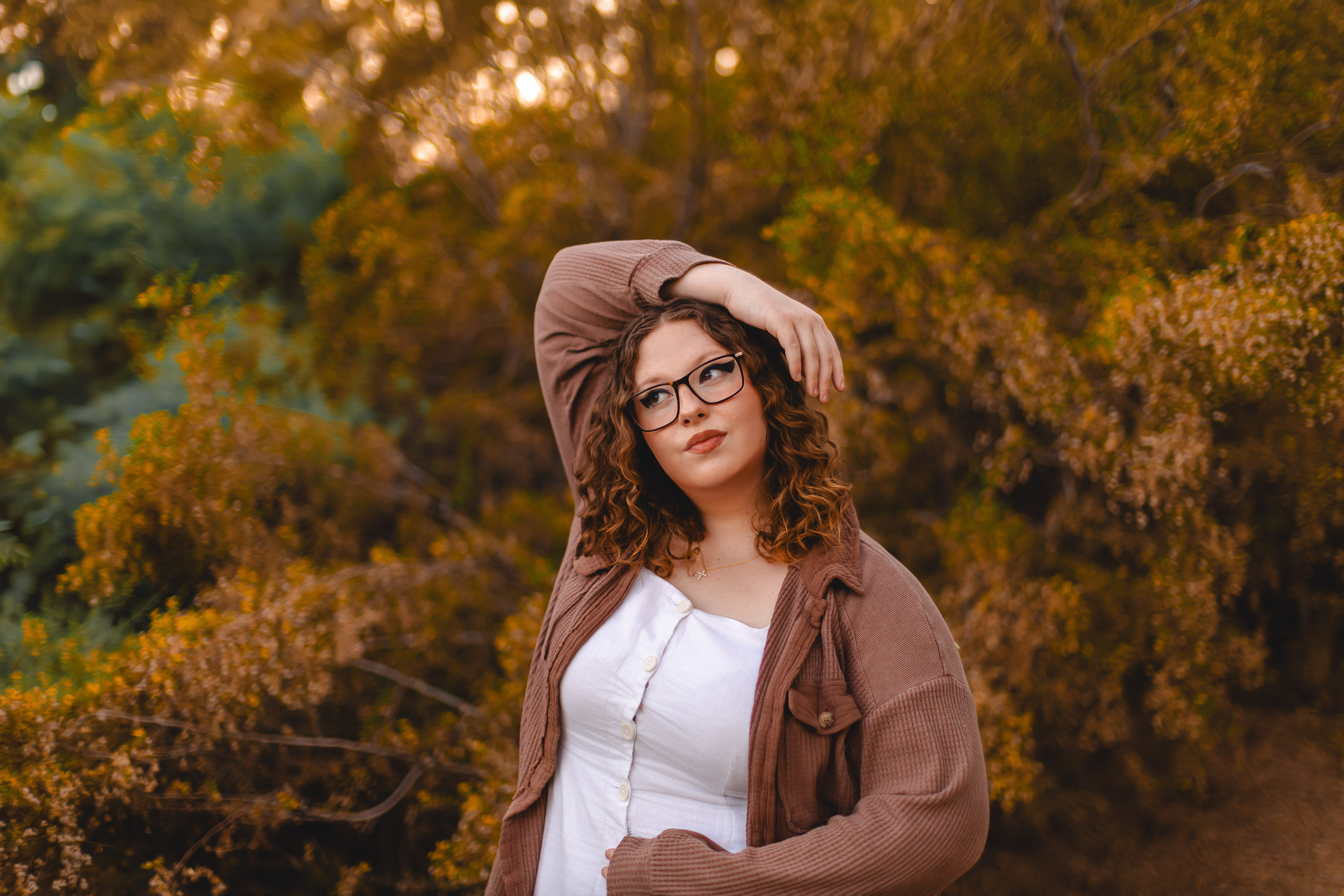 High school senior girl posing among golden autumn foliage at Riparian Preserve in Gilbert, Arizona, photographed by Andria May Photography