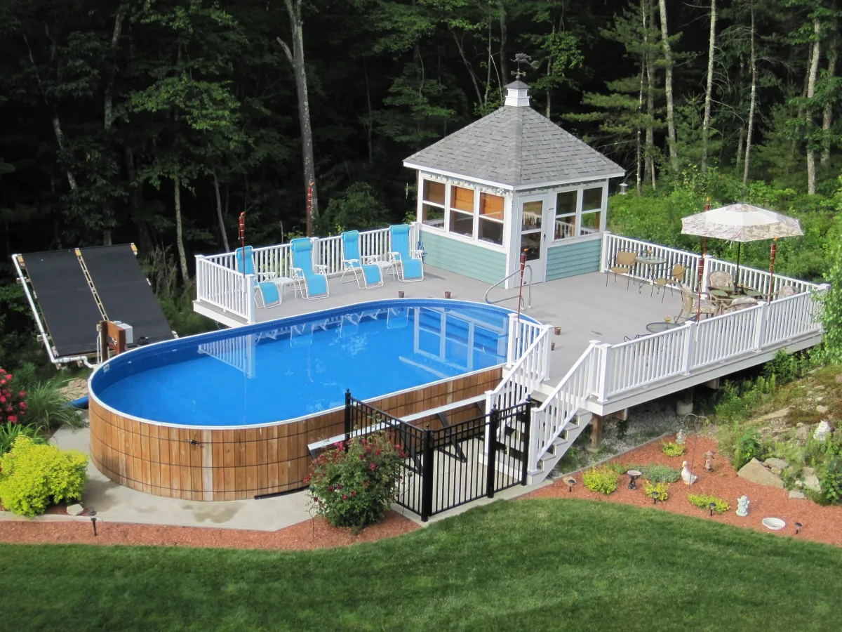 A confident small business owner in branded workwear stands beside a partially installed round wooden pool, tools in hand, with a bright, modern outdoor setting and clear blue sky. The image is crisp, vibrant, and inviting, emphasizing professionalism and opportunity.