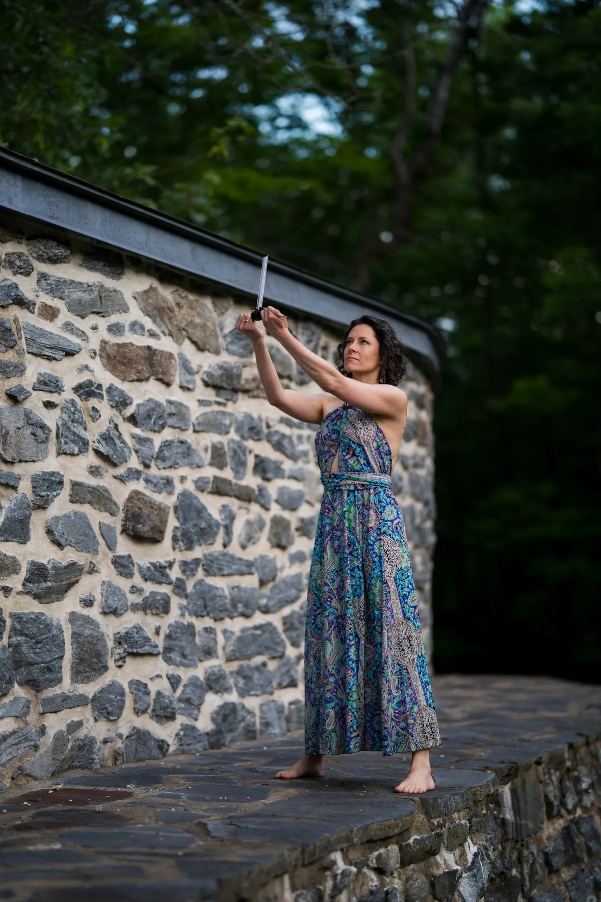 Annie Burelle, praticienne en soins énergétiques, tient une antenne de Lecher dans un paysage d’automne au coucher du soleil