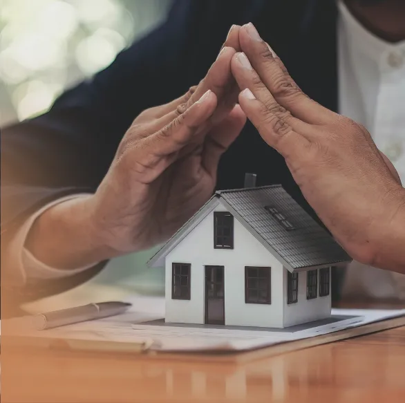 close up shot of a hand performing a house gesture over a miniature model of a house
