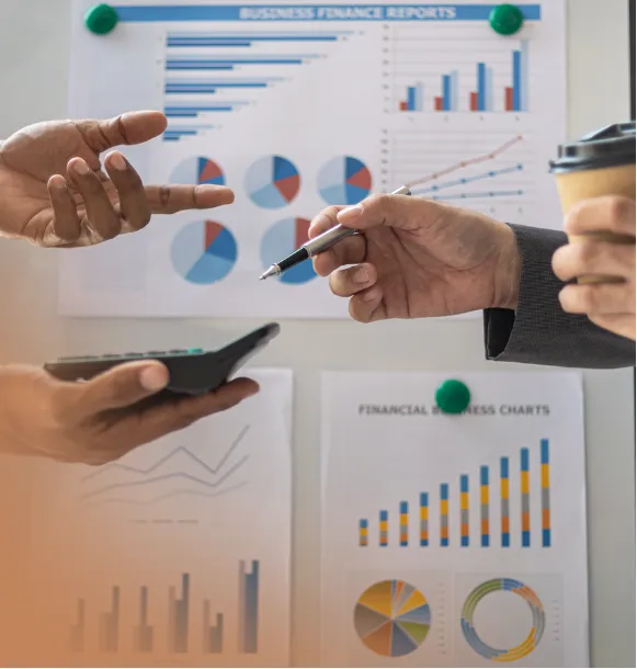 close up shot of the hands of two people holding a calculator and a pen discussing about numbers and charts