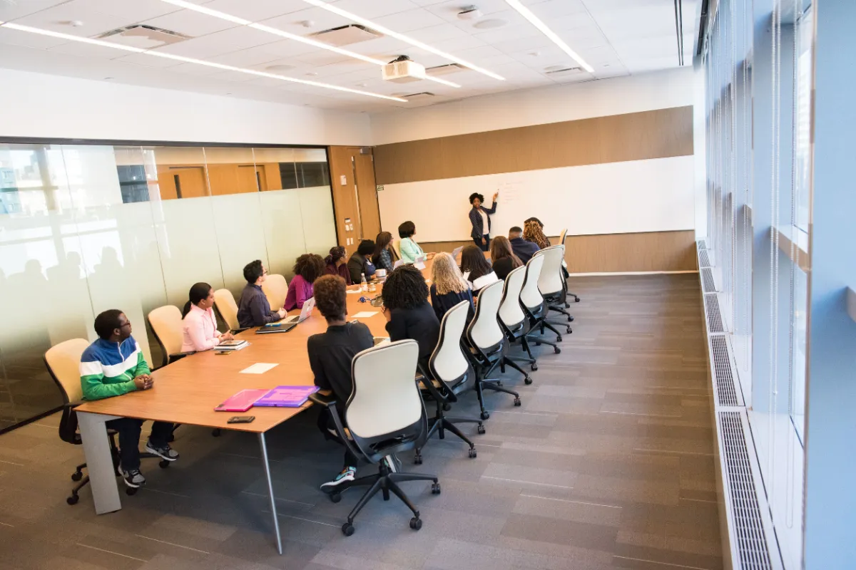 Small group in a modern conference room with a facilitator leading discussion, illustrating the programme’s design for 5–20 participants to ensure genuine participation.