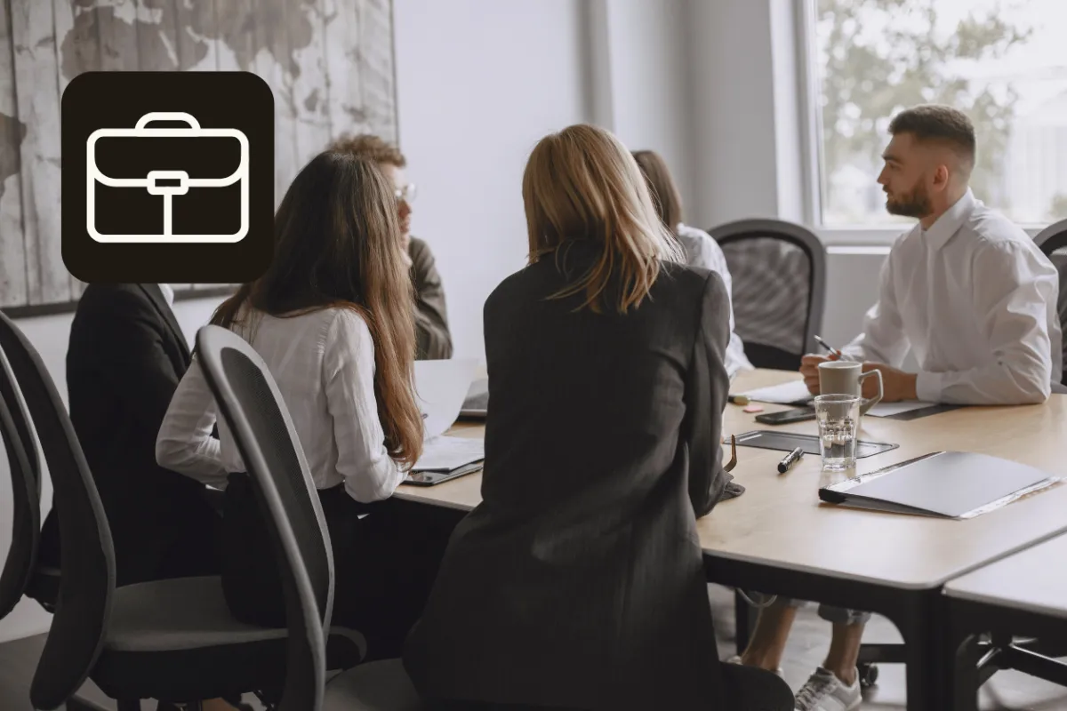 Team gathered around a conference table in a modern office, engaged in discussion during the Executive Performance Programme that helps participants recognise pressure patterns and respond more deliberately.