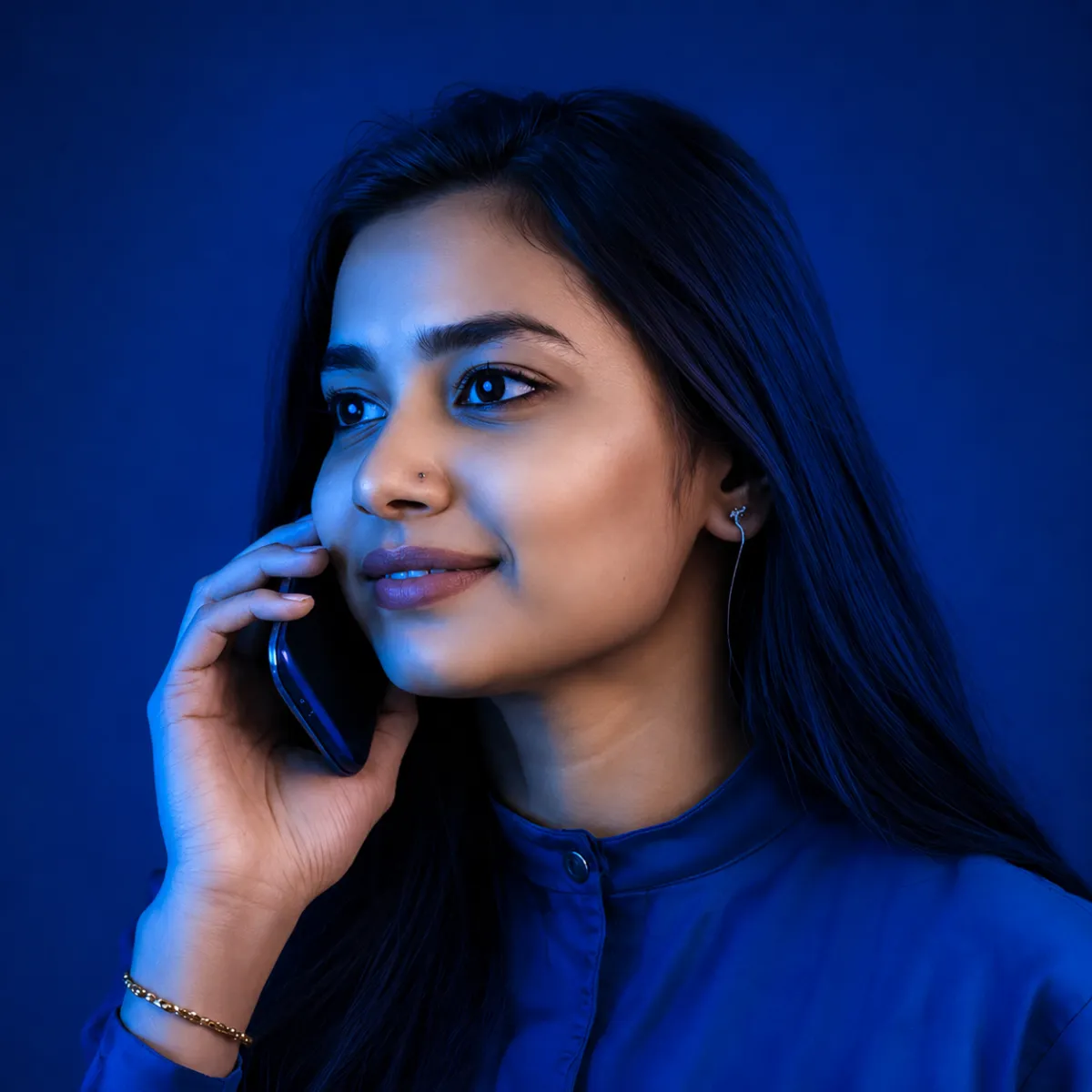 Woman on a phone call, brightly lit with purple and blue tones, looking slightly upward with a calm expression.
