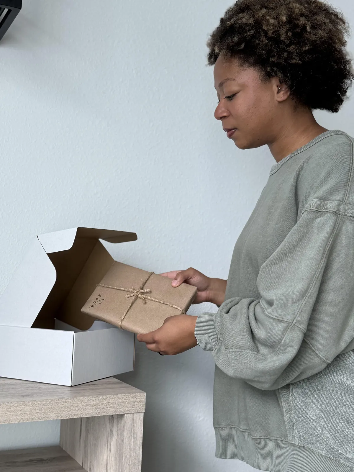 woman puts curated book into a quarterly book club subscription box