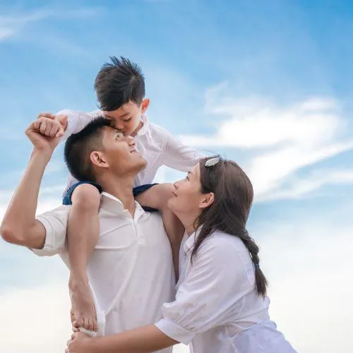 man holding a child above its head and his wife hugging him