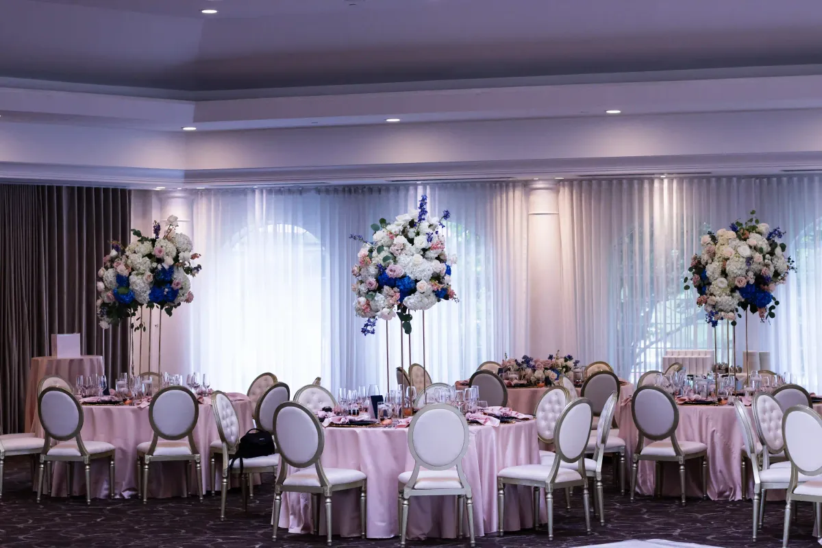 Réception en salle de bal avec grands centres de table bleus et rose poudré