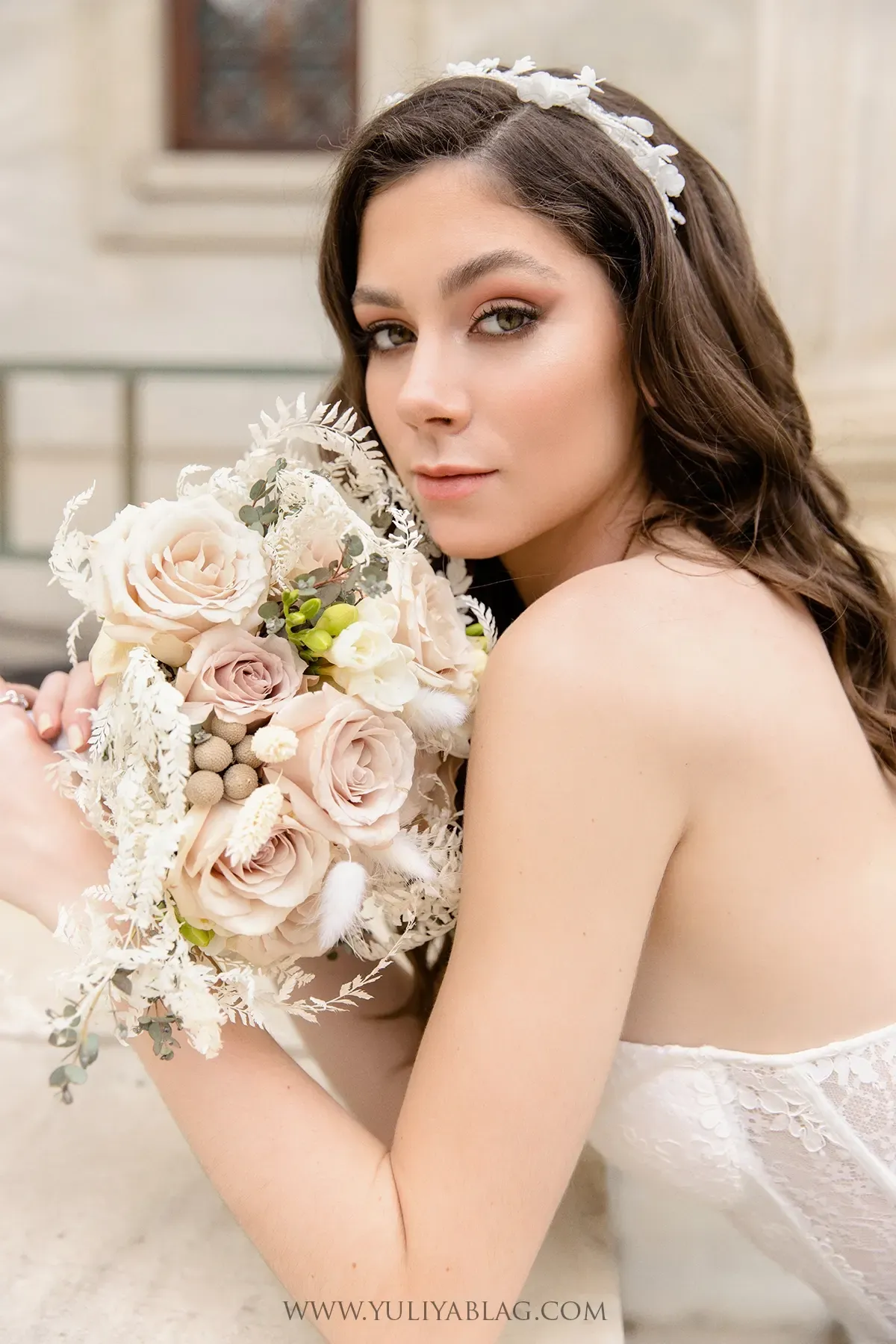 Mariée tenant un bouquet de roses poudrées sur son épaule