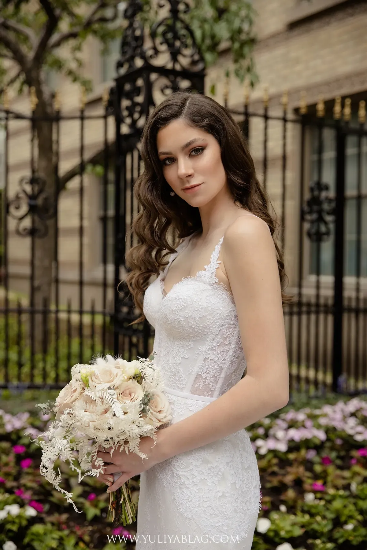 Mariée dans un jardin tenant un bouquet rose poudré et ivoire