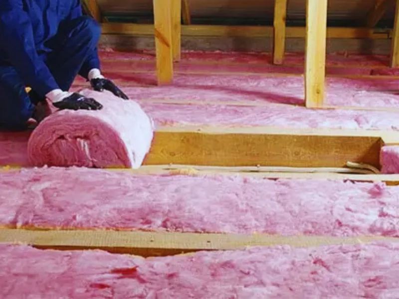 rolling out fiberglass insulation in attic