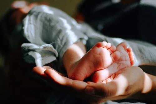 Woman cupping a newborn baby’s feet