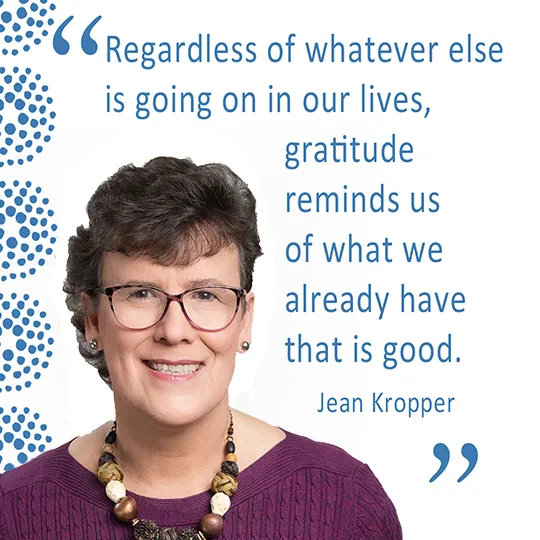 A portrait of Jean Kropper wearing a purple sweater and glasses, with a quote: 'Regardless of whatever else is going on in our lives, gratitude reminds us of what we already have that is good