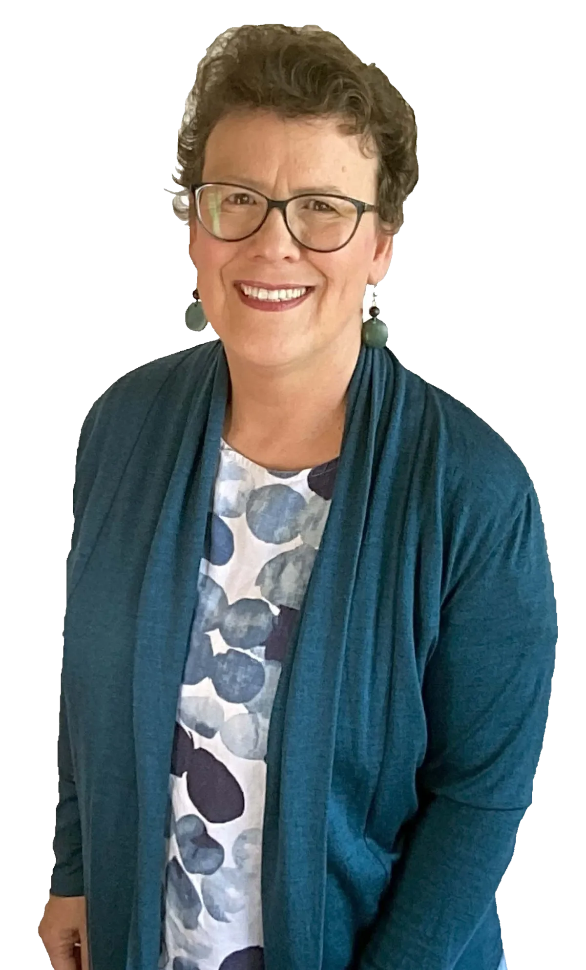 Portrait of Jean Kropper, a smiling woman with short curly hair, wearing glasses, a blue top, a navy cardigan, and a long necklace, standing against a plain white background.