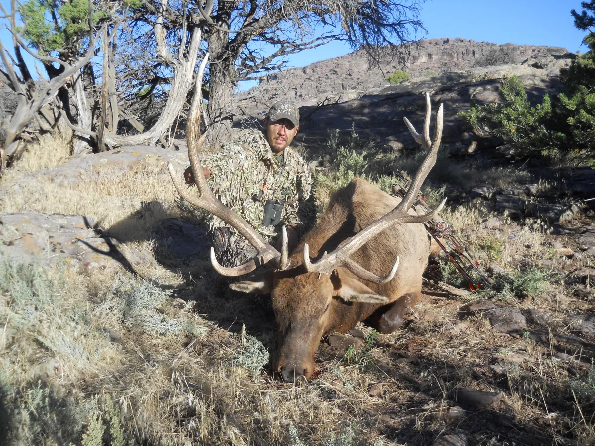 man in brown jacket and black pants sitting on brown grass field during daytime
