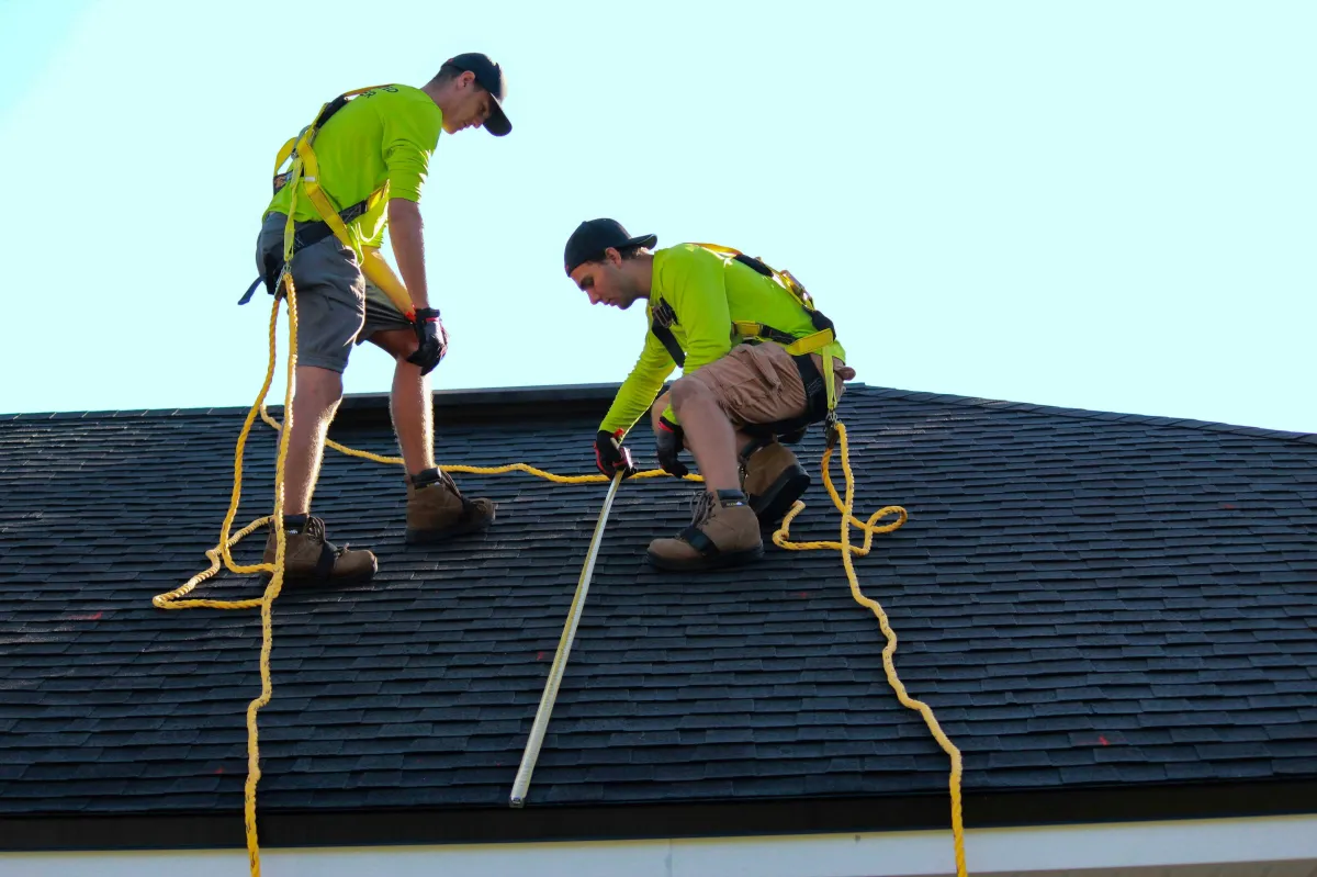 a man in a yellow shirt is working on a roof