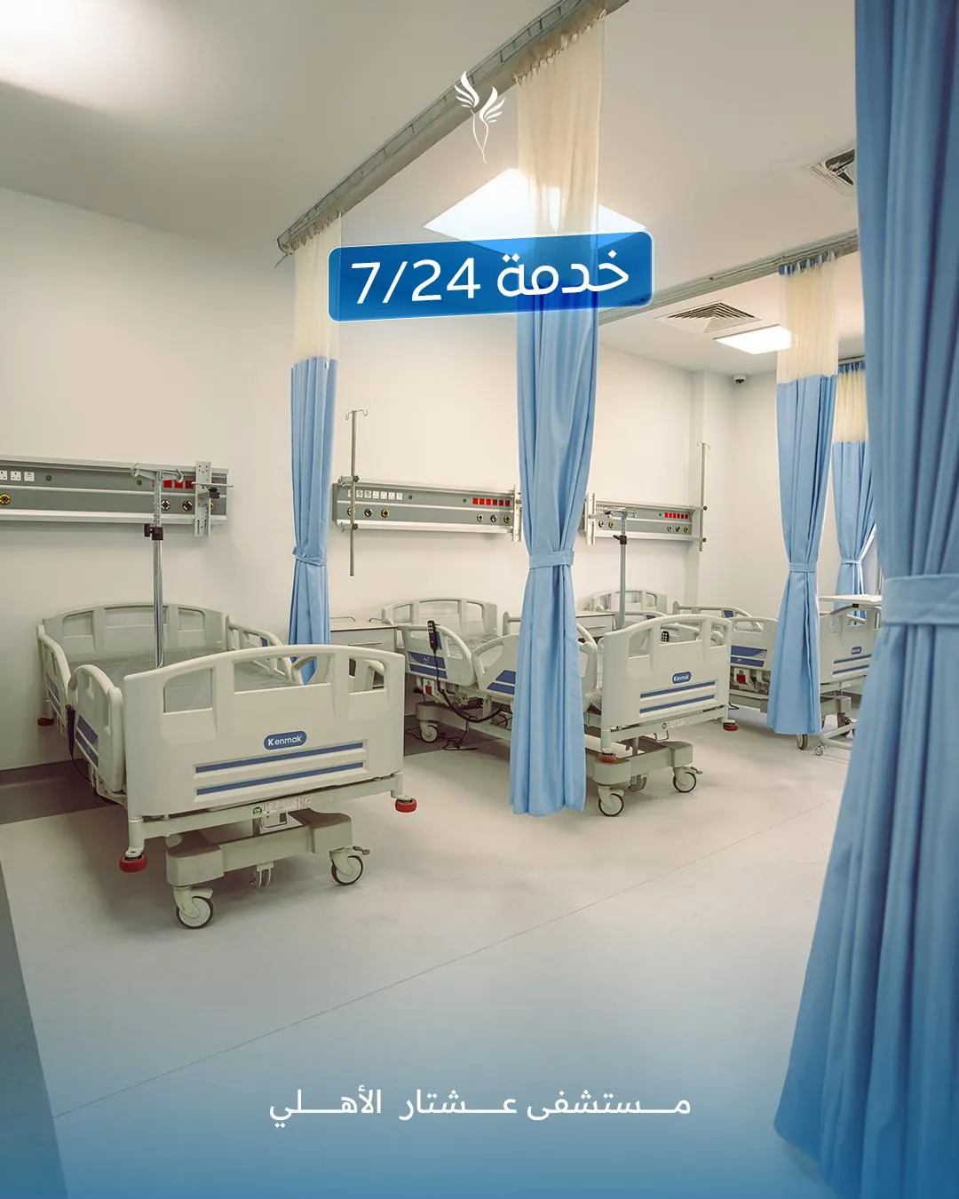 Hospital room with multiple patient beds and blue curtains, featuring "24/7" service signage, representing Ishtar Hospital's commitment to round-the-clock care in critical and emergency services.