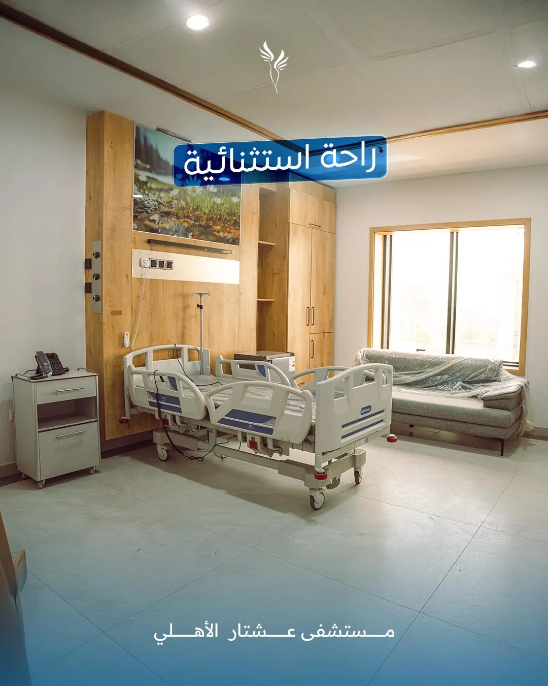 Hospital room featuring a modern hospital bed, a comfortable sofa, and a large window, emphasizing a serene and welcoming environment at Ishtar Private Hospital.