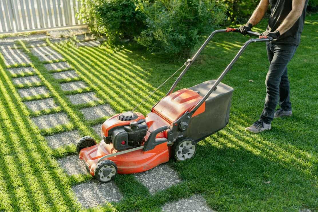 orange lawn mower side view over stepping stones and grass