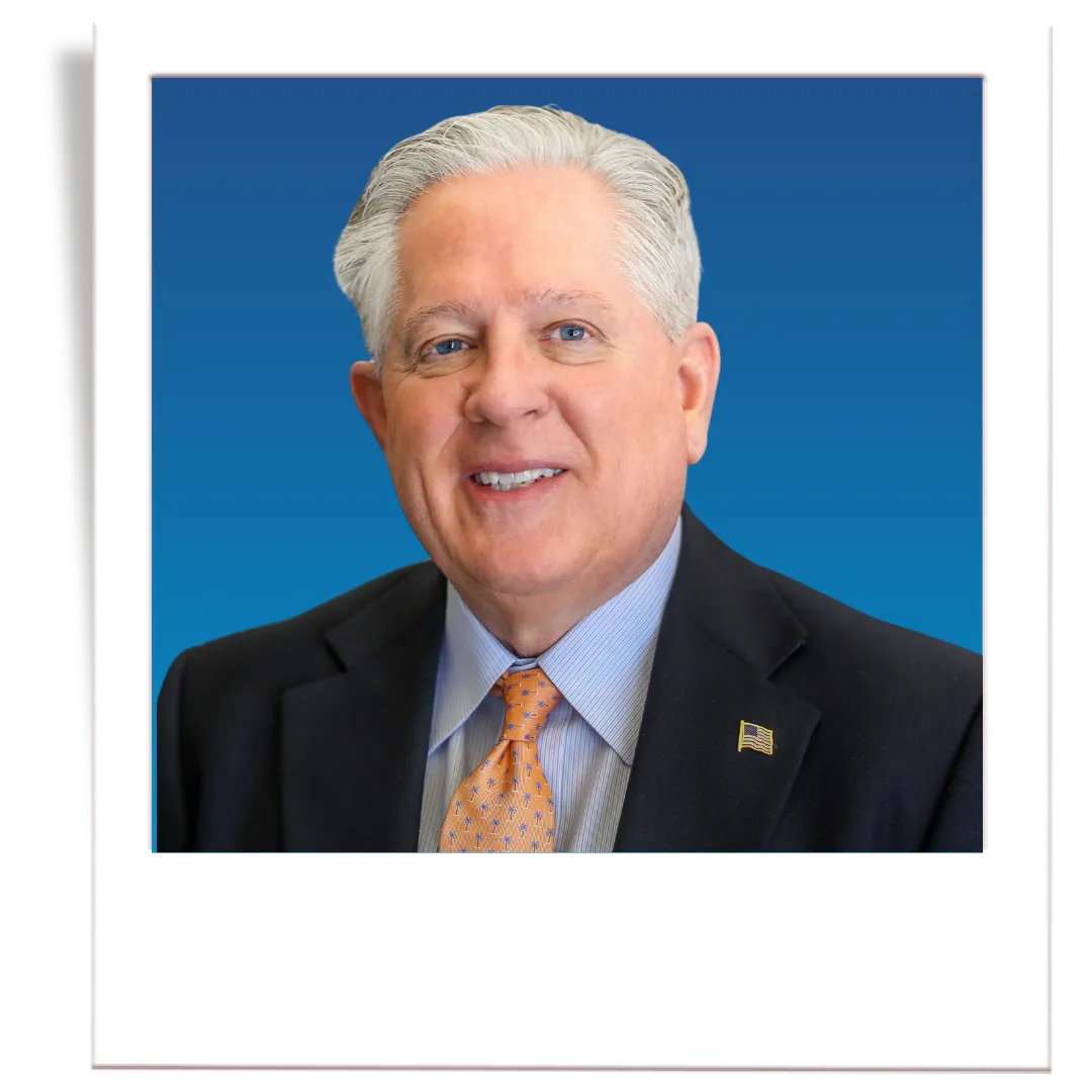 Headshot of Dennis Corbett on a polaroid with a blue background.