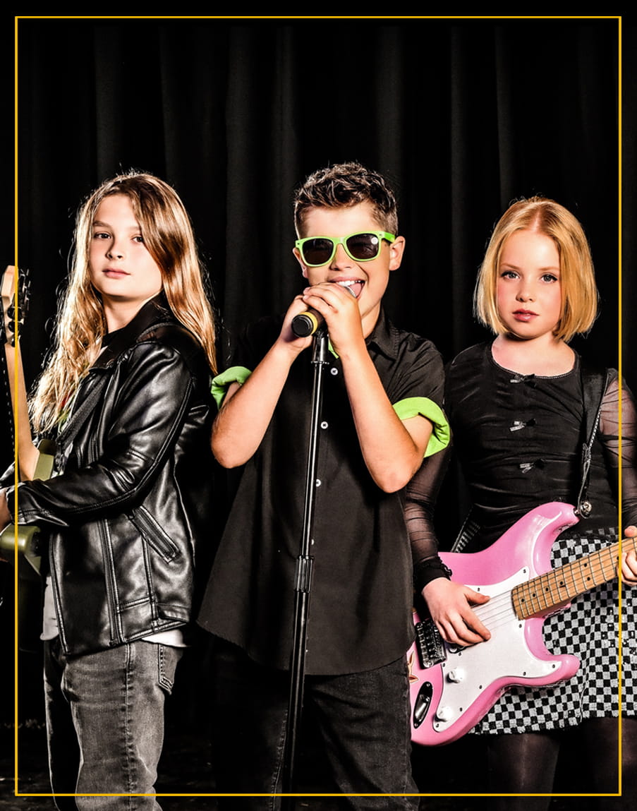 Group of teens playing guitar, bass, and singing during a Rockstars of Tomorrow band lesson program.