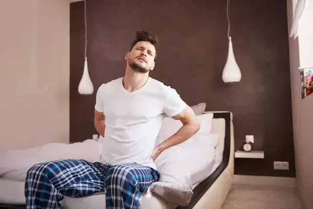 man with back pain getting out of bed