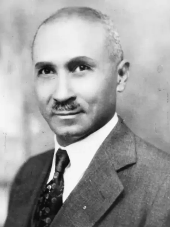 Portrait of a Bishop College alumnus, a Black educator standing before a bookshelf.