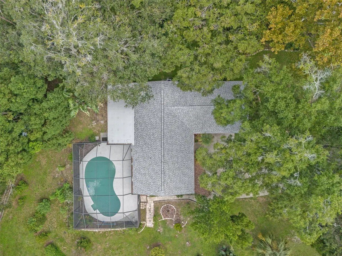 Aerial listing photograph of the home, private pool and tree-lined setting at 22002 Darley Place.