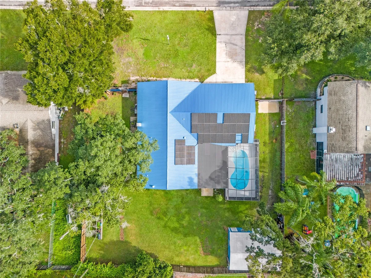 Aerial listing photograph of 116 Windy Circle, showing the metal roof, solar panels, screened pool and workshop.