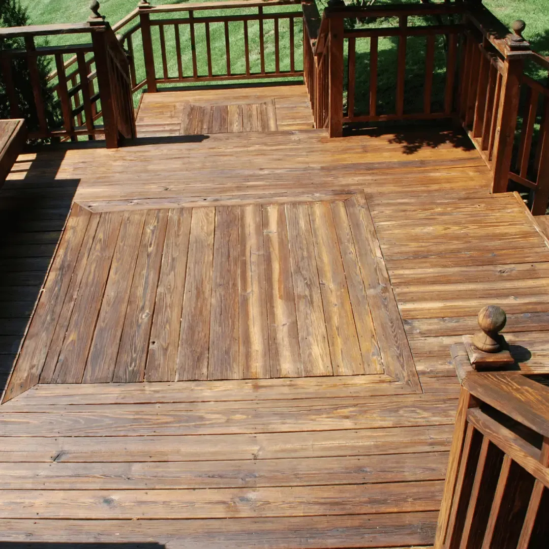An newly installed wooden deck. There are two raised sections that appear to be trap doors or access panels. The deck railings and steps are also made of wood.