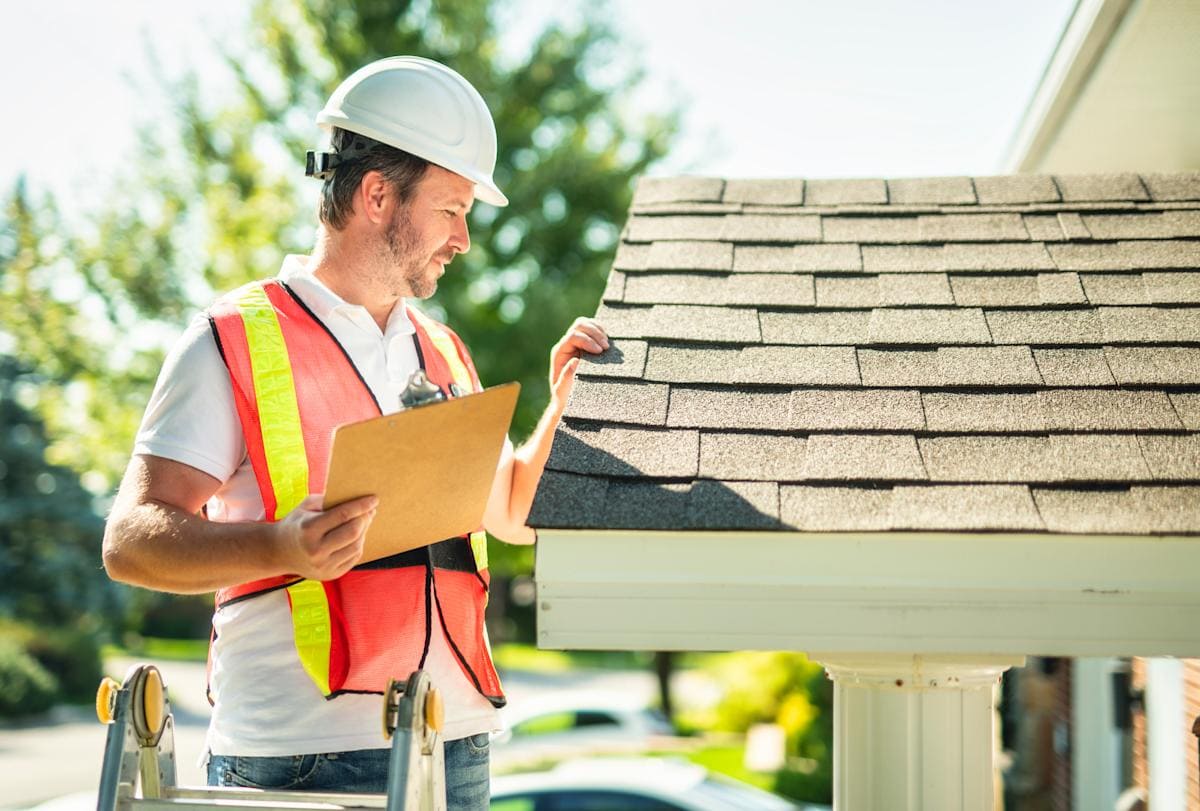 Roofing professional inspecting asphalt shingles during a residential roof assessment to identify potential maintenance and repair needs.