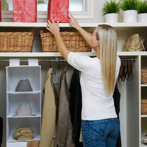 Woman organizing closet shelves with baskets and storage bins for better home organization