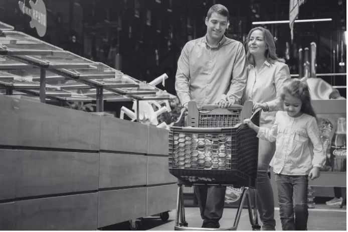 Two adults and a child shopping together with a trolley in a busy retail environment.