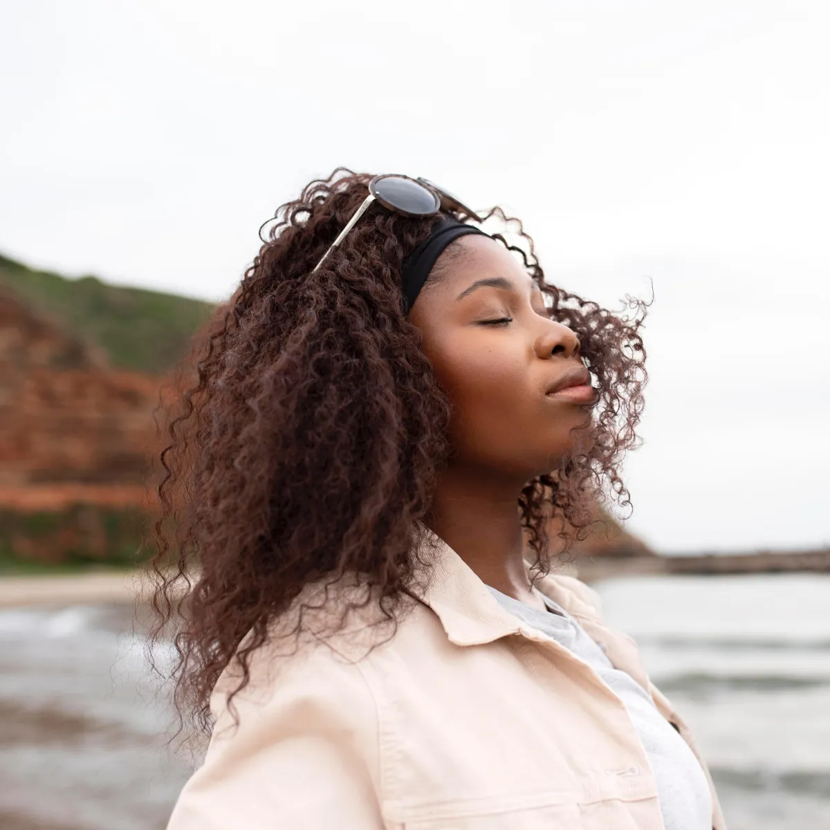 Woman breathing deeply outdoors, reflecting a calm, regulated nervous system.