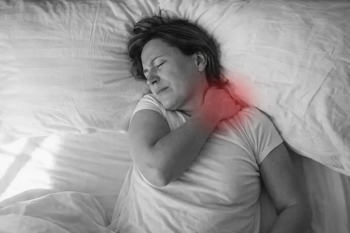 Mulher deitada na cama com dor no ombro