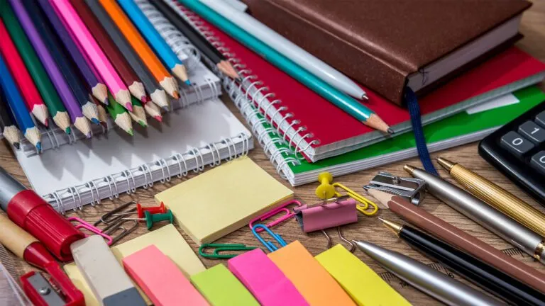 A desk cluttered with various school supplies, including pens, notebooks, and stationery items.