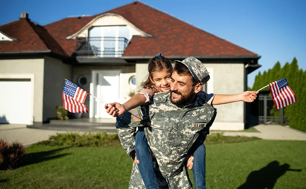 U.S. Army service member and daughter celebrating outside their new Massachusetts home purchased with a VA loan
